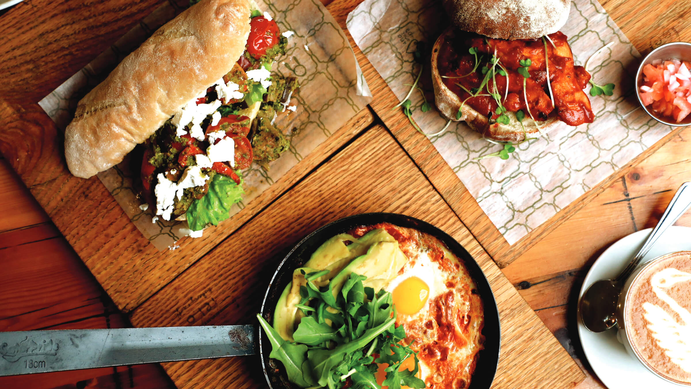 Ciabatta sandwich, sourdough toast and a baked egg skillet on wooden boards