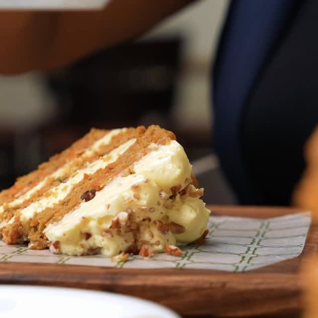 Slice of layered cake with cream and nuts on baking paper